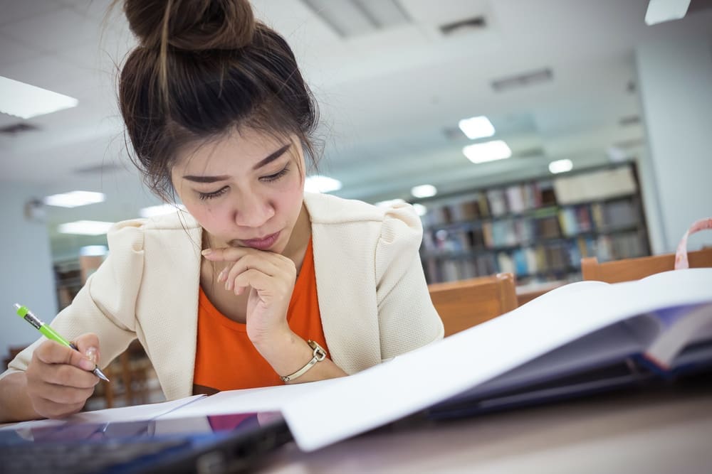 student working on college essay in library